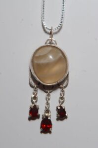 Low moon pendant: argentium silver, honey calcite, and garnets